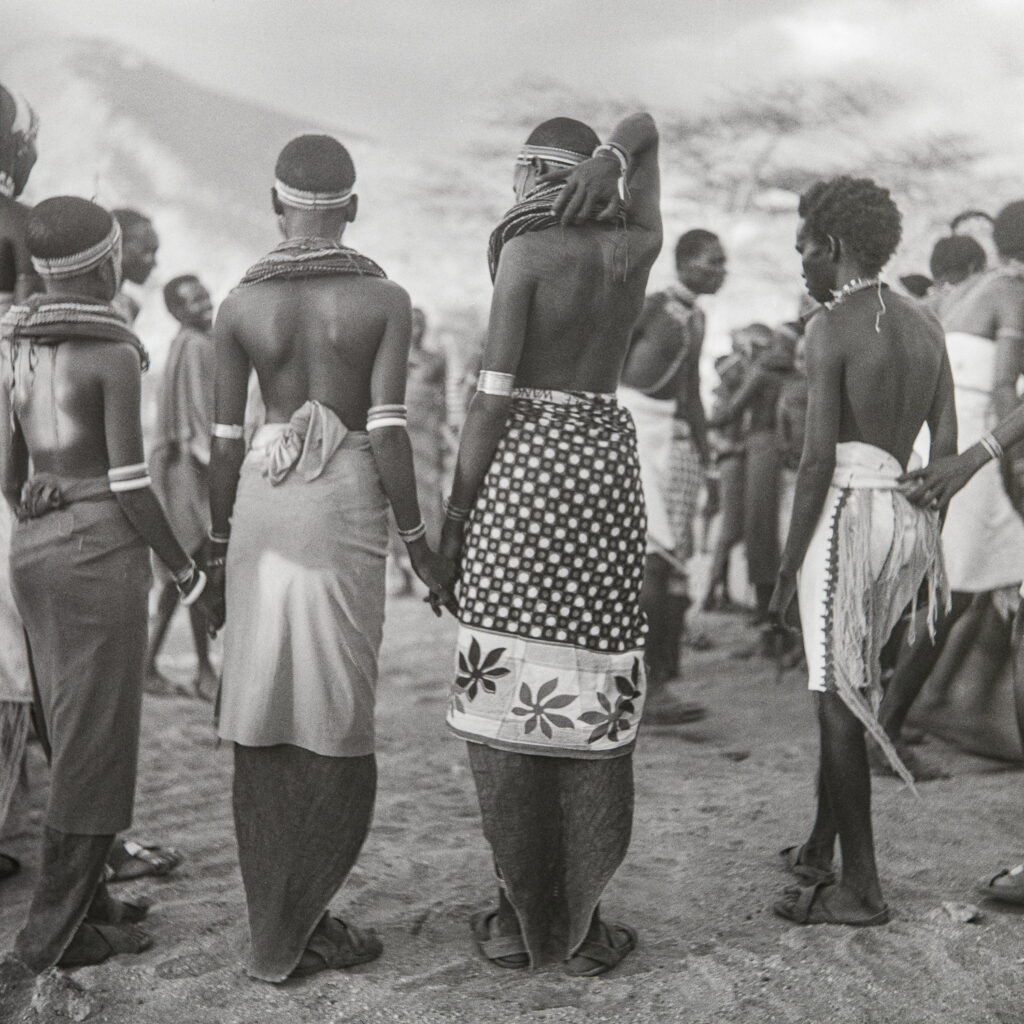 Young Samburu look on as others perform a farewell dance