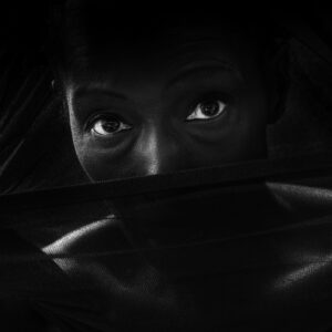 Close-up portrait of Alison Limerick with her face partially covered, eyes looking directly at the camera.