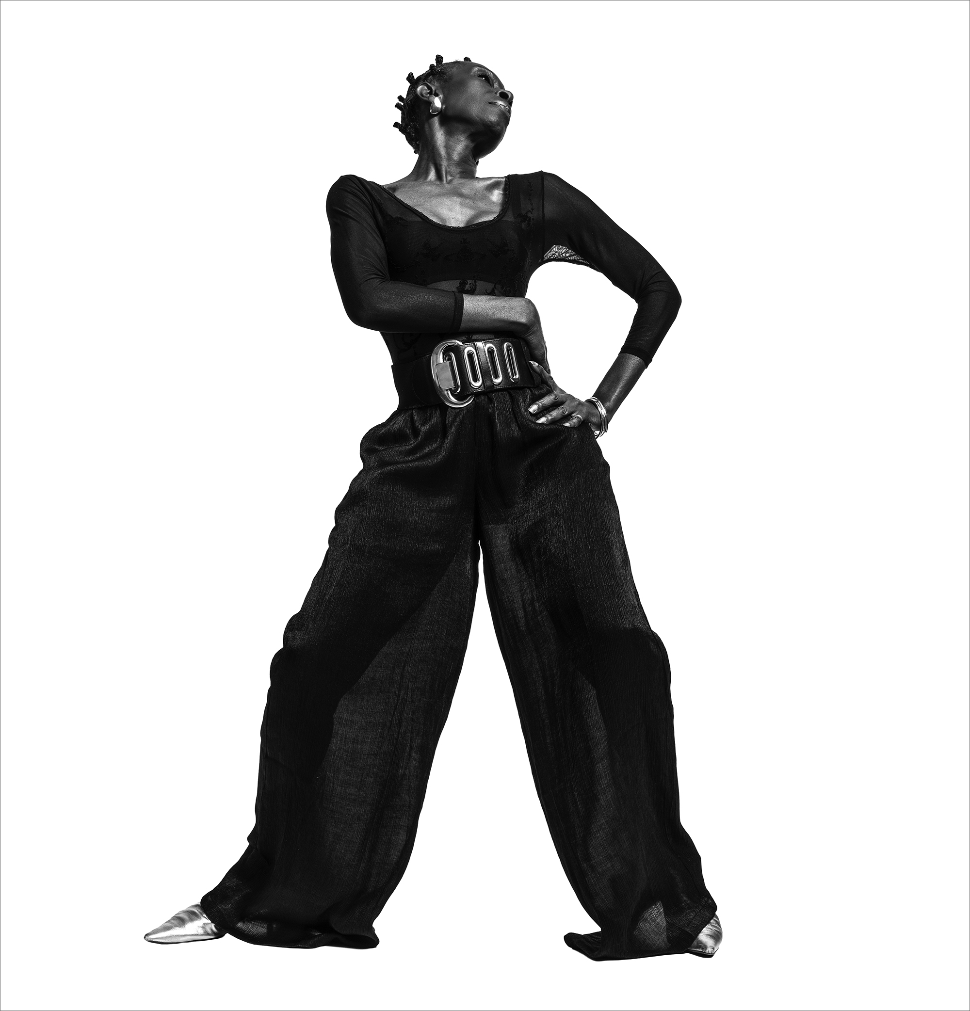 Alison Limerick standing in a confident pose, wearing wide-leg trousers and a sheer top against a plain background.